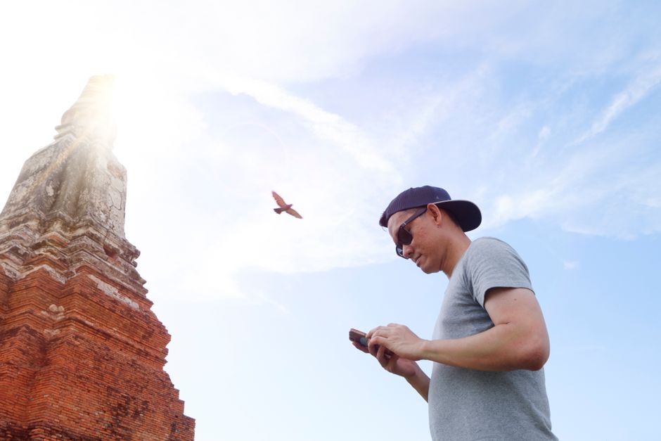 Voyageur utilisant son smartphone près d’un temple en Thaïlande