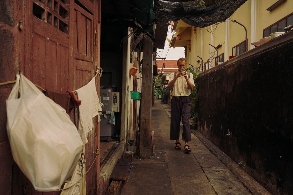 Voyageur utilisant son smartphone dans une ruelle de Bangkok
